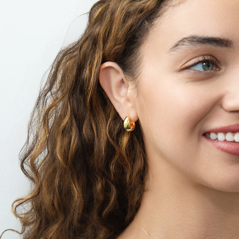 Model wearing Oval Dome Small Huggie Earrings in Sterling Silver 0.6 inch, Yellow Gold Flashed