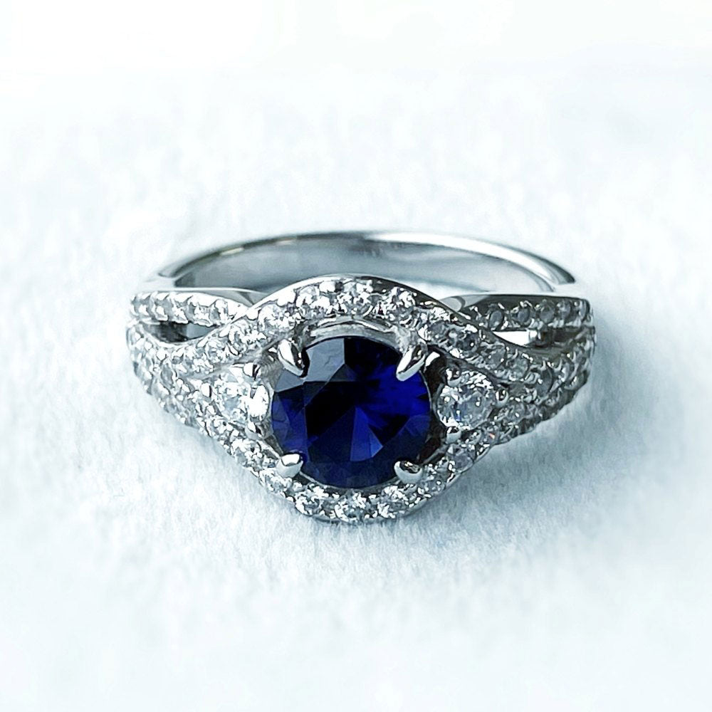 Flatlay view of 3-Stone Woven Simulated Blue Sapphire Round CZ Ring in Sterling Silver