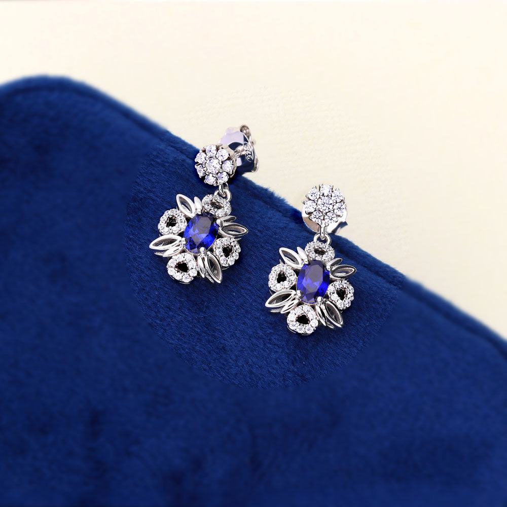 Flatlay view of Flower Halo Simulated Blue Sapphire CZ Earrings in Sterling Silver