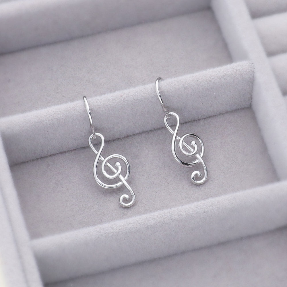 Flatlay view of Treble Clef Music Note Fish Hook Dangle Earrings in Sterling Silver