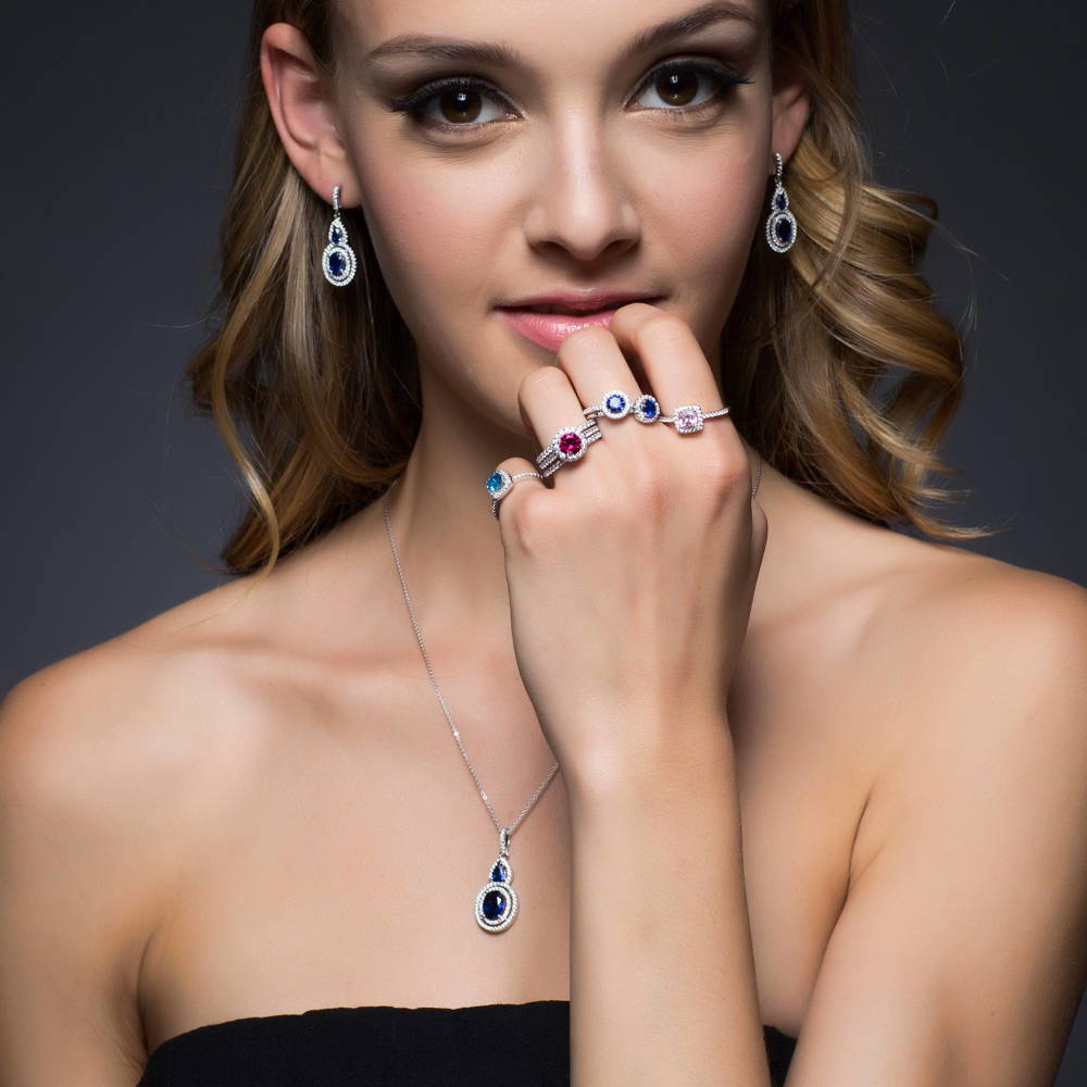 Model wearing Halo Simulated Blue Sapphire Oval CZ Dangle Earrings in Sterling Silver