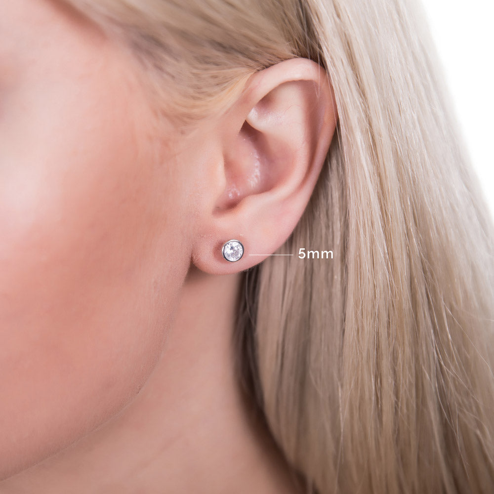 Model wearing Solitaire Bezel Set Round CZ Stud Earrings in Sterling Silver