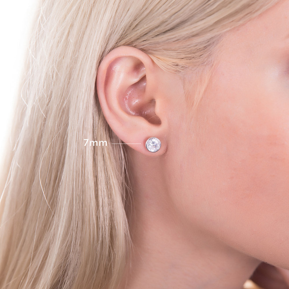 Model wearing Solitaire Bezel Set Round CZ Stud Earrings in Sterling Silver