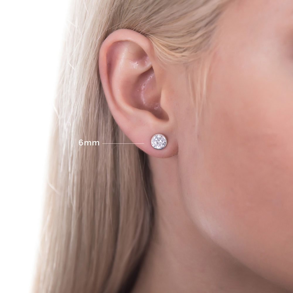 Model wearing Solitaire Bezel Set Round CZ Stud Earrings in Sterling Silver