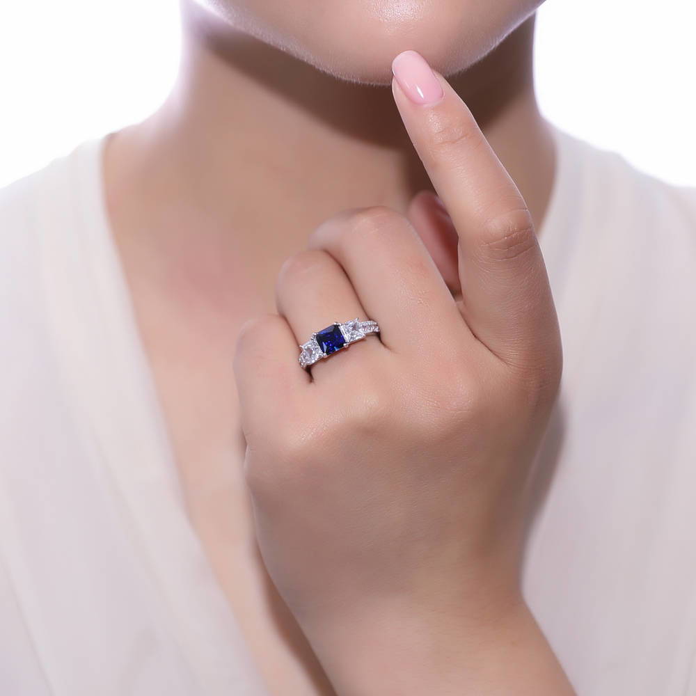 Model wearing 3-Stone Simulated Blue Sapphire Princess CZ Ring in Sterling Silver