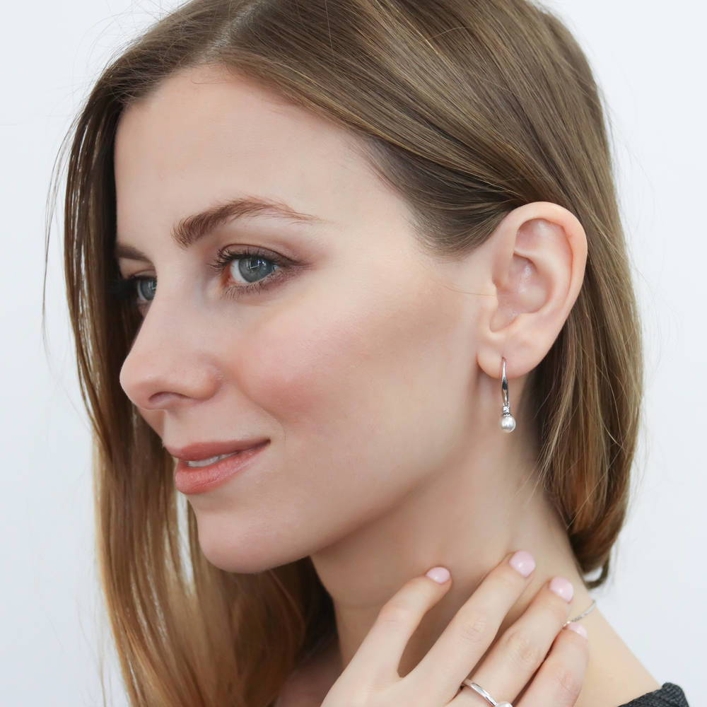 Model wearing Solitaire White Round Imitation Pearl Earrings in Sterling Silver