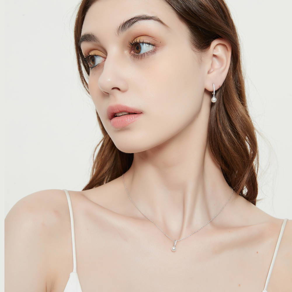 Model wearing Solitaire White Round Imitation Pearl Earrings in Sterling Silver