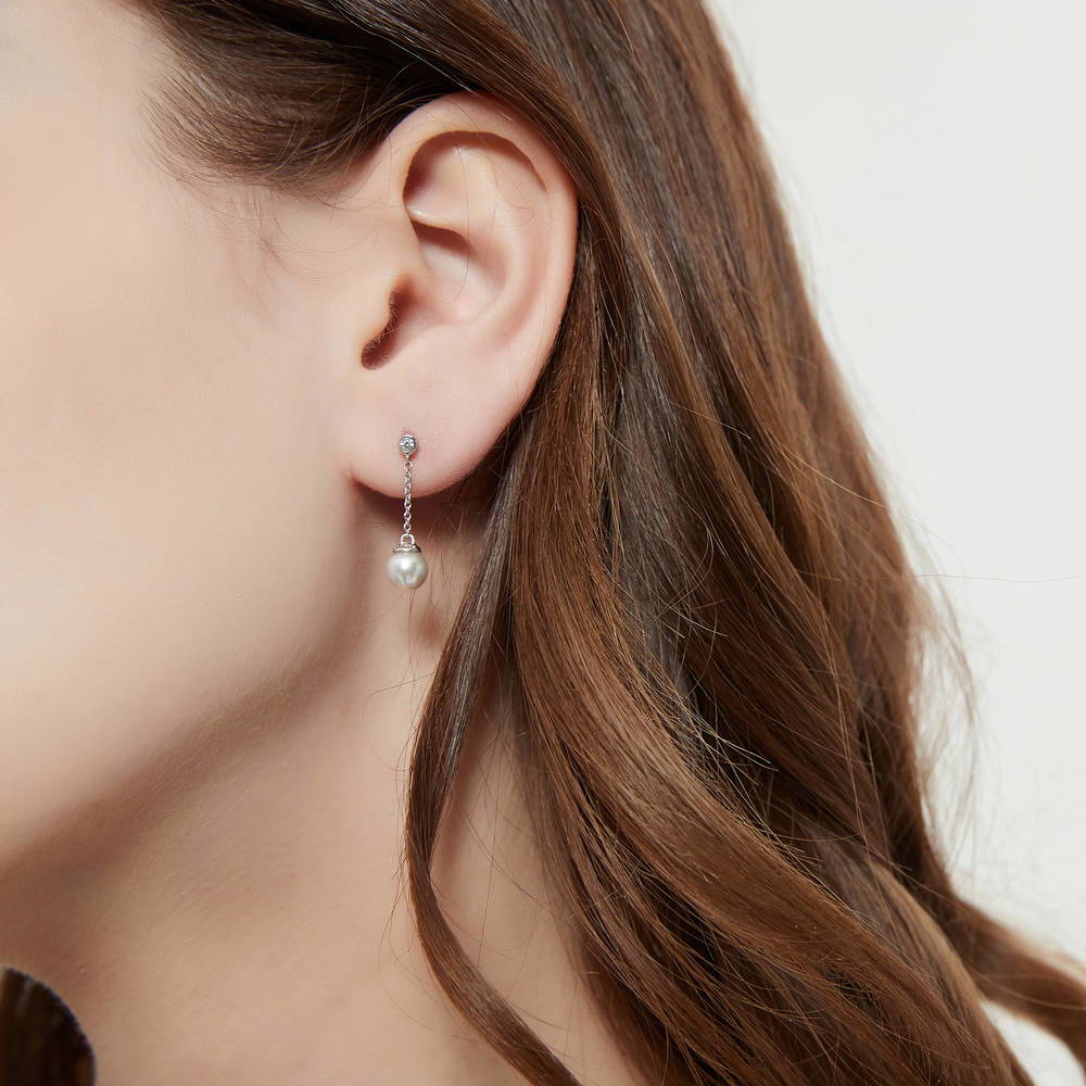 Model wearing Solitaire White Round Imitation Pearl Earrings in Sterling Silver