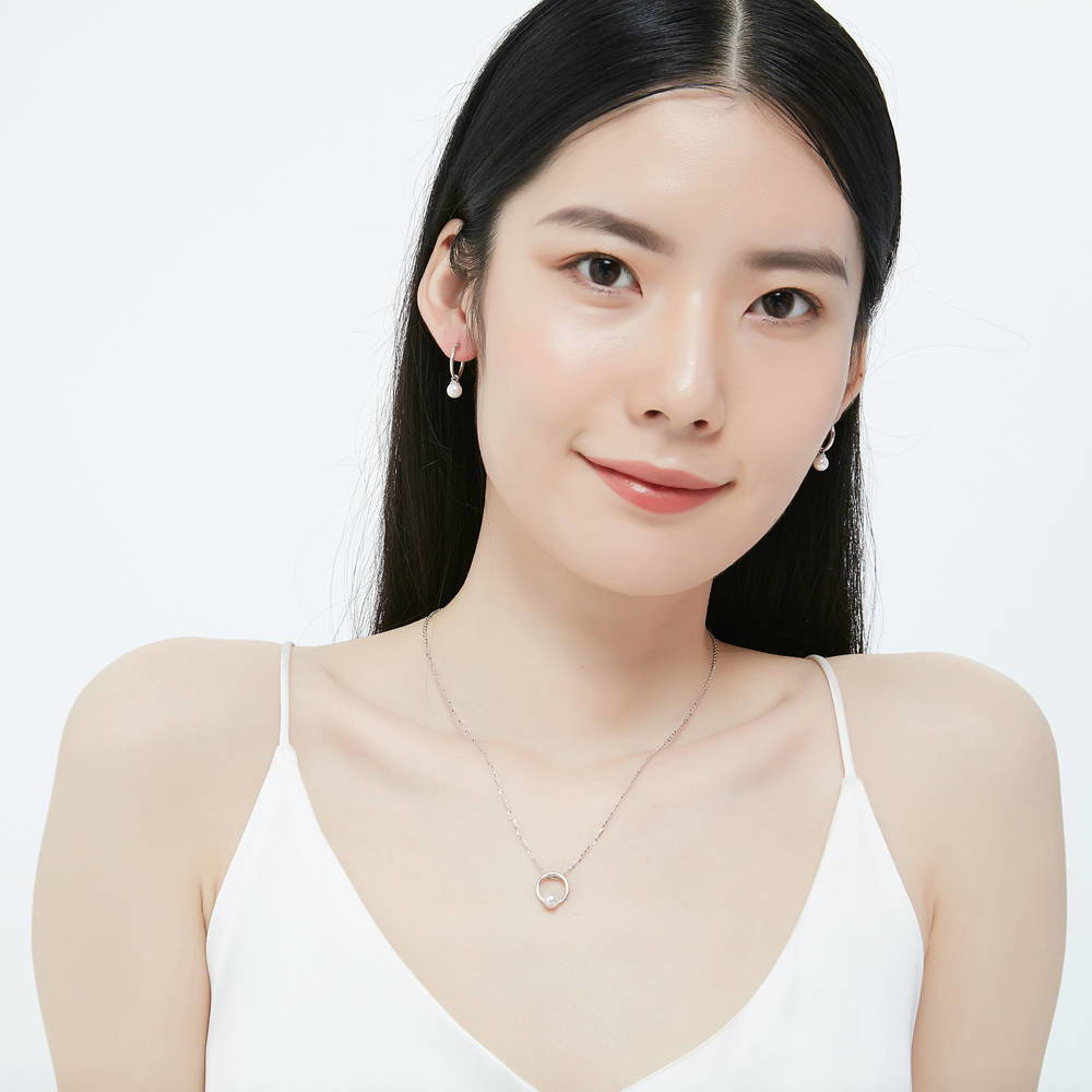 Model wearing Solitaire White Round Imitation Pearl Earrings in Sterling Silver