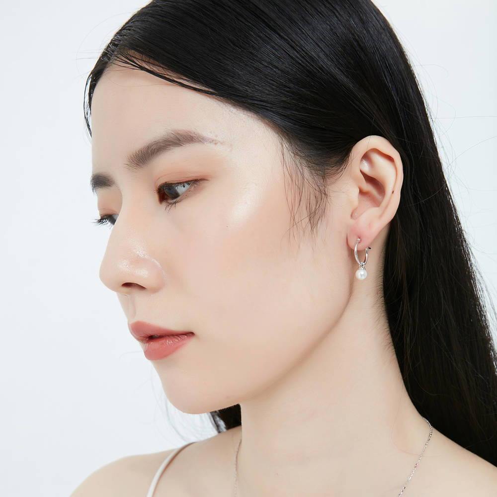 Model wearing Solitaire White Round Imitation Pearl Earrings in Sterling Silver