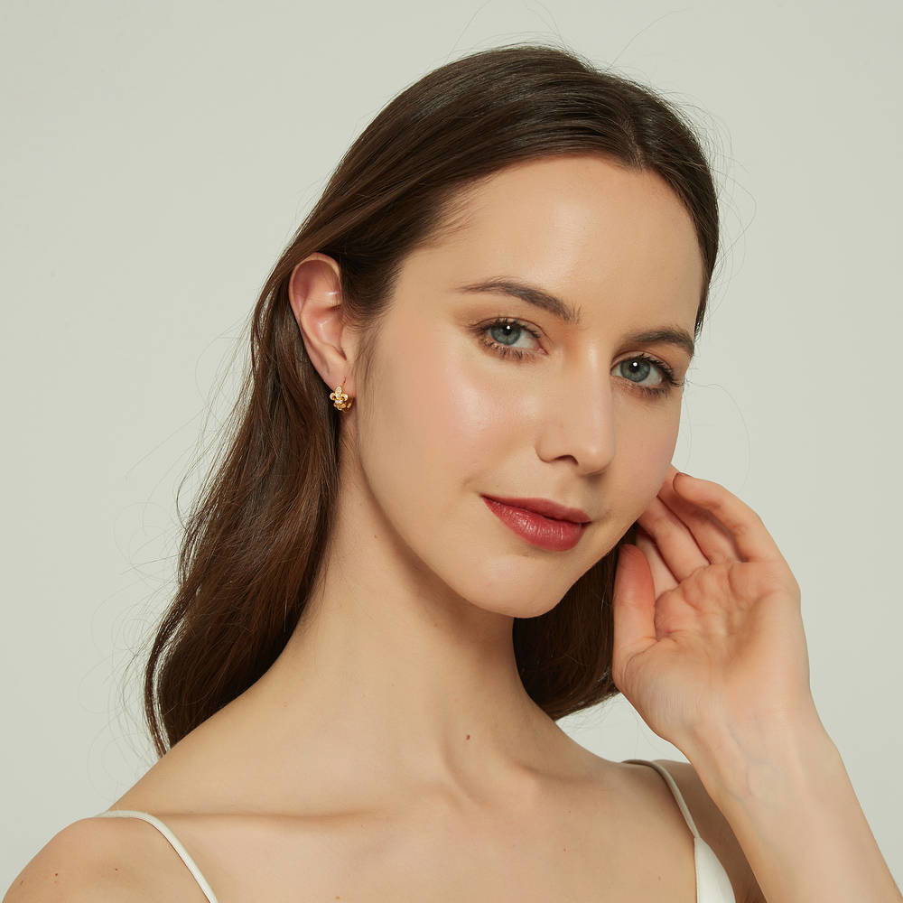 Model wearing Fleur De Lis CZ Small Huggie Earrings in Sterling Silver 0.5 inch