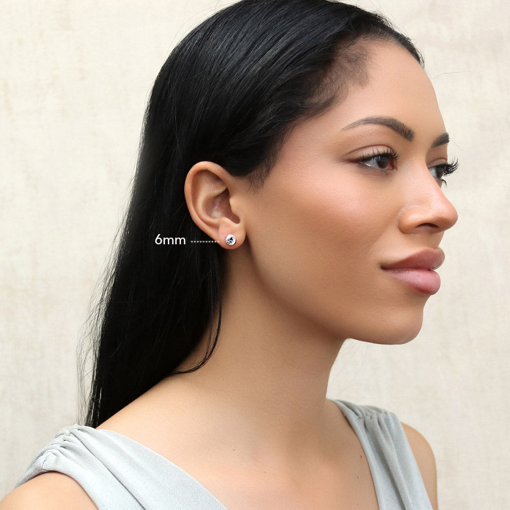Model wearing Solitaire Bezel Set Round CZ Stud Earrings in Sterling Silver