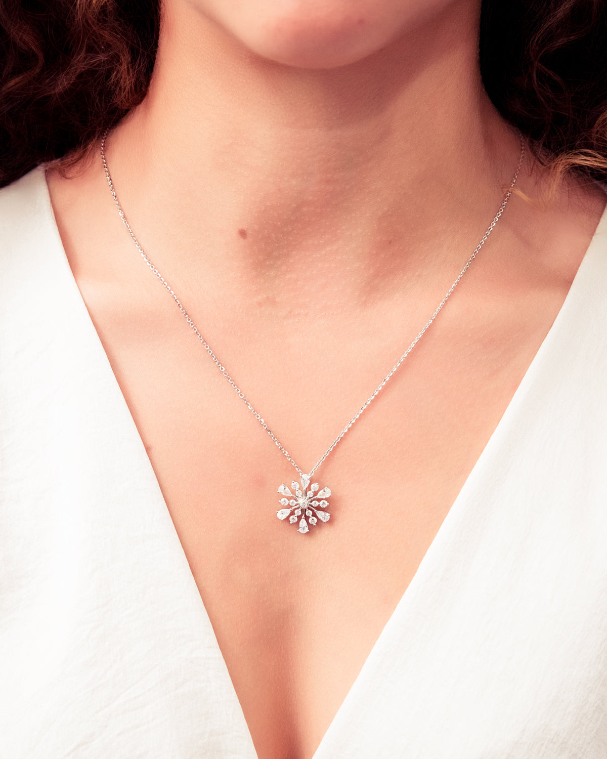 Necklace with a snowflake pendant worn by a model against a white background