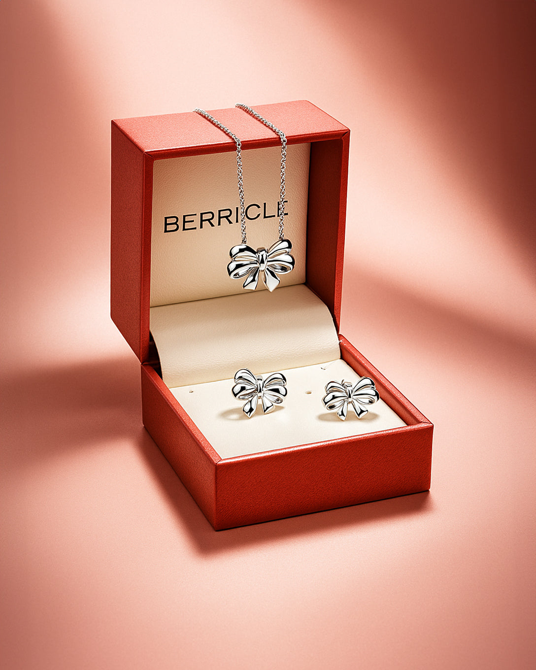 Silver bow-shaped jewelry set in a Berricle box on a pink background