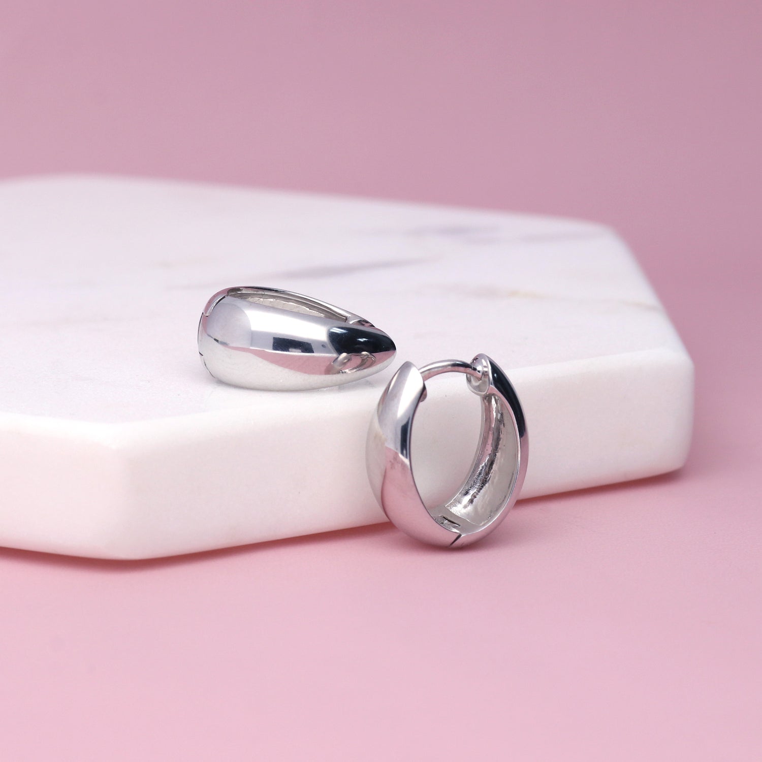 Flatlay view of Oval Dome Small Huggie Earrings in Sterling Silver 0.6 inch, Yellow Gold Flashed