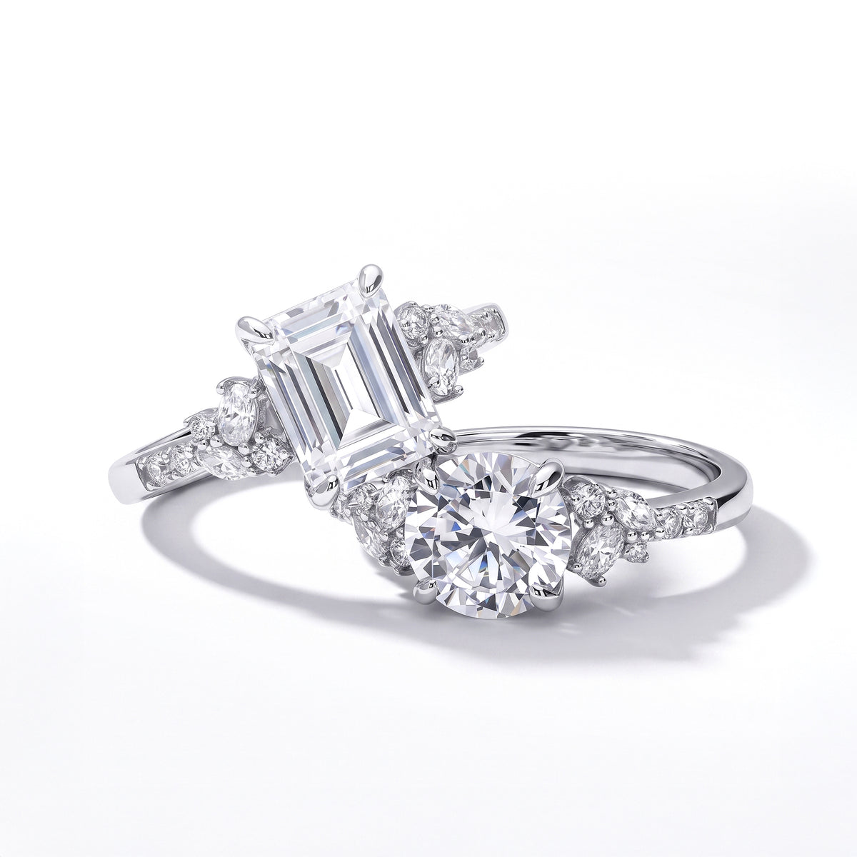 Two sterling silver rings featuring emerald-cut and round clear stones, accented with marquise and round stones along the bands.