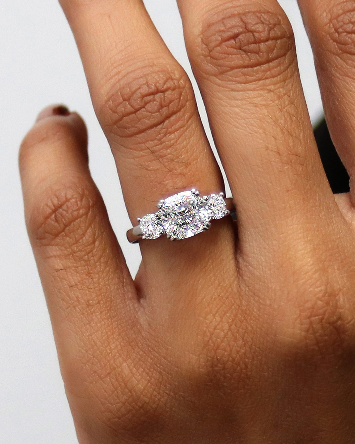 3-stone cushion ring on a finger
