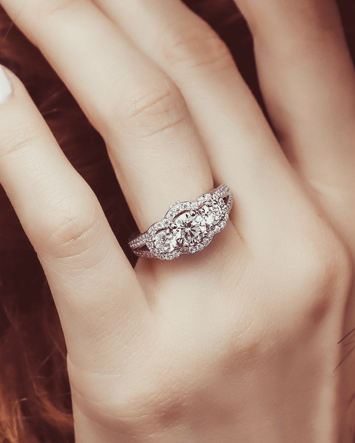 3-stone halo ring on a finger