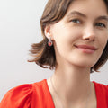 Model wearing Halo Clover Oval CZ Earrings in Sterling Silver, Red Color