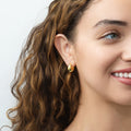 Model wearing Oval Dome Small Huggie Earrings in Sterling Silver 0.6 inch, Yellow Gold Flashed