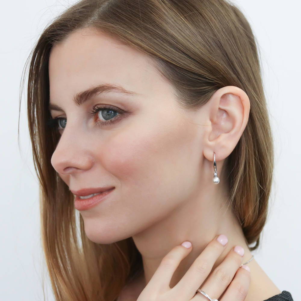 Model wearing Solitaire White Round Imitation Pearl Earrings in Sterling Silver, 2 of 5