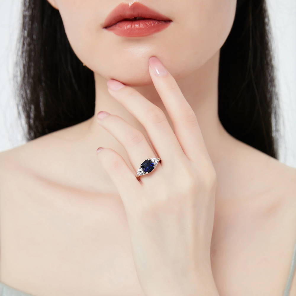 Model wearing 3-Stone Simulated Blue Sapphire Cushion CZ Ring in Sterling Silver, 2 of 11