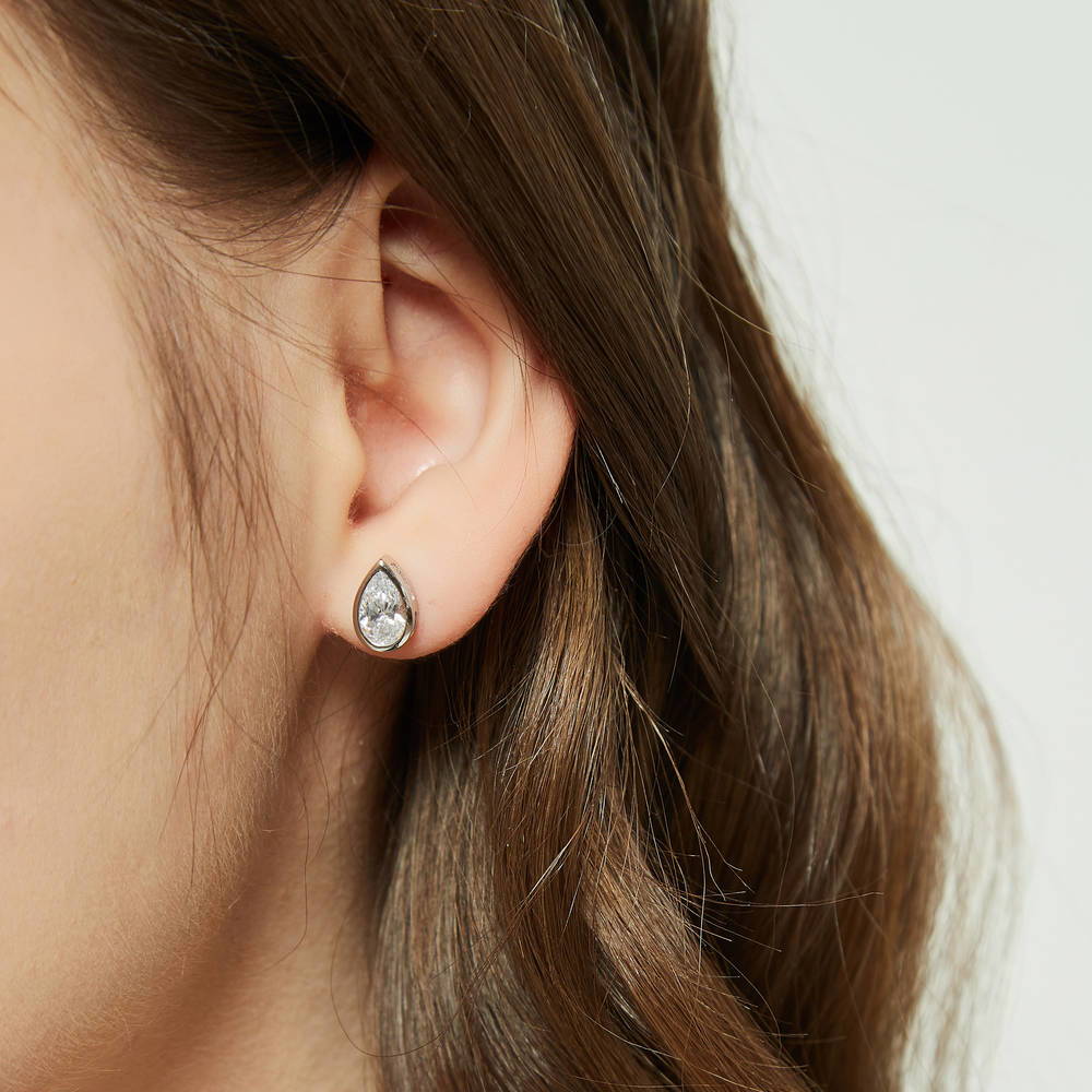 Model wearing Solitaire 1.6ct Bezel Pear CZ Stud Earrings in Sterling Silver, 4 of 7