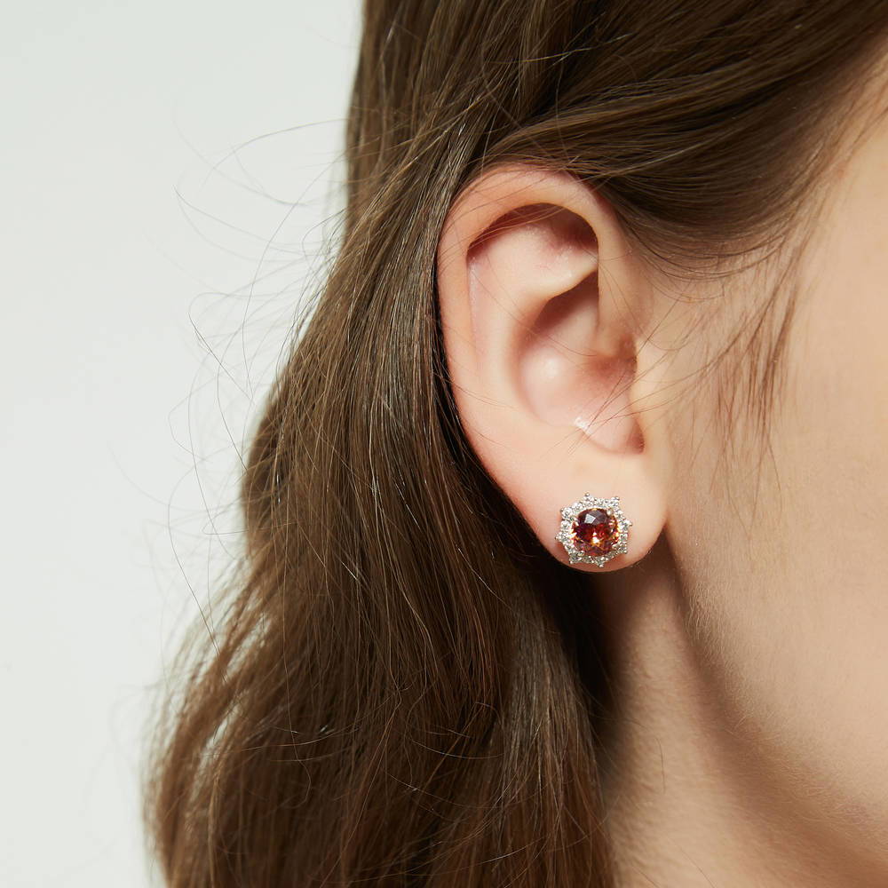 Model wearing Sunburst Halo CZ Stud Earrings in Sterling Silver, Red Orange Color