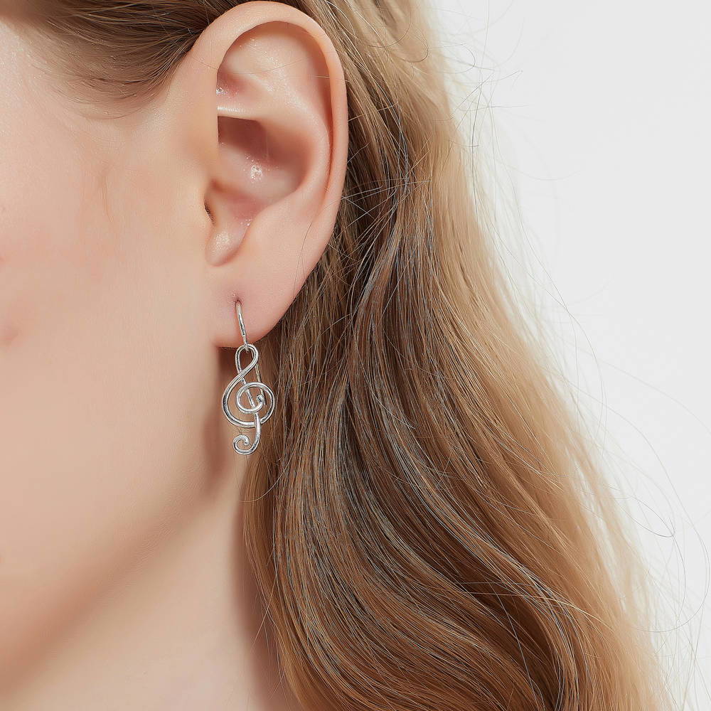 Model wearing Treble Clef Music Note Fish Hook Earrings in Sterling Silver, 2 of 8