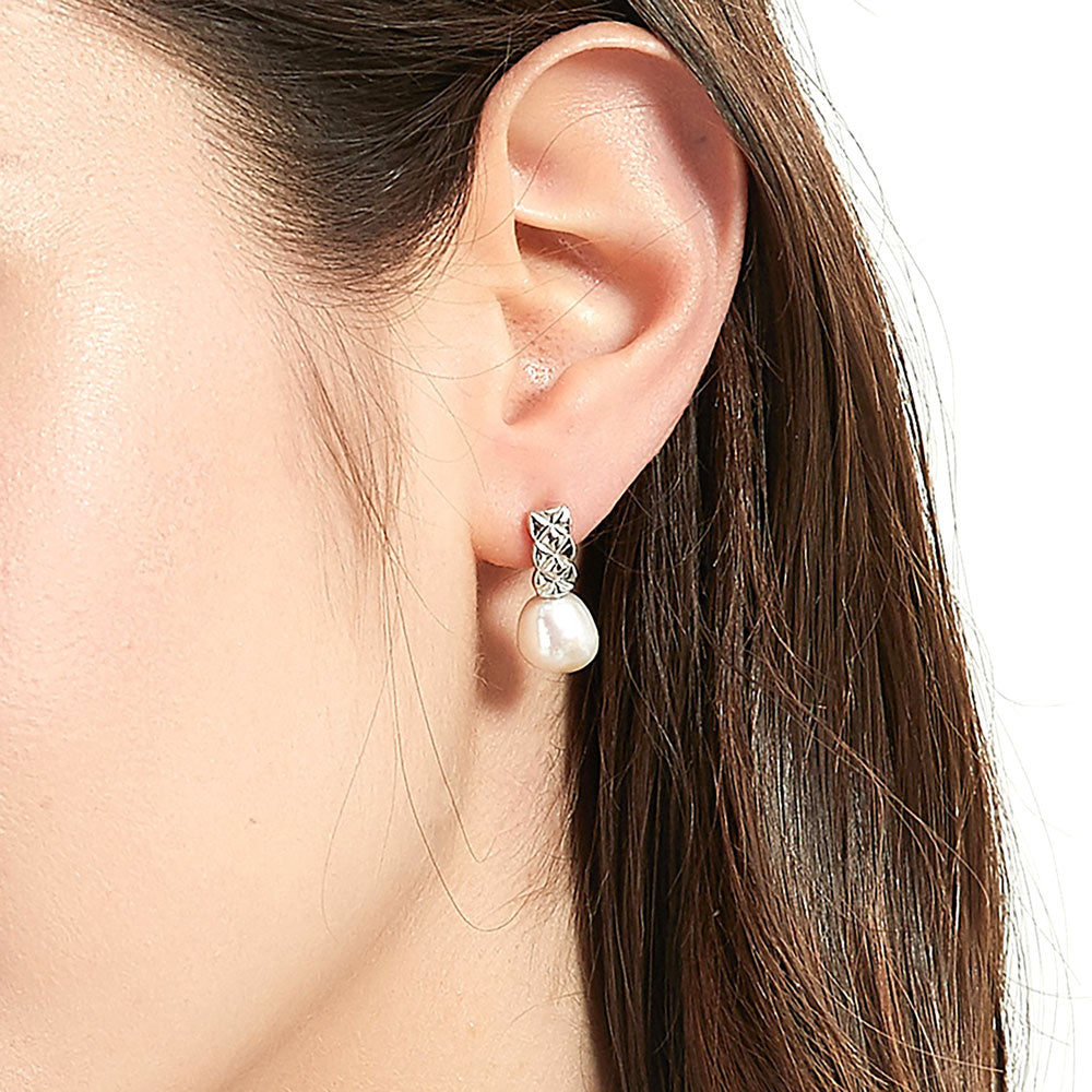 Model wearing Solitaire Baroque Cultured Pearl Stud Earrings in Sterling Silver, Yellow Gold Flashed