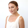 Model wearing Fleur De Lis CZ Mini Huggie Earrings in Sterling Silver 0.5 inch, Rhodium Plated